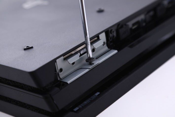 Step 1）首先把 PS4 Pro 背面的硬碟外蓋拆開，並且解除硬碟架的鎖定螺絲。