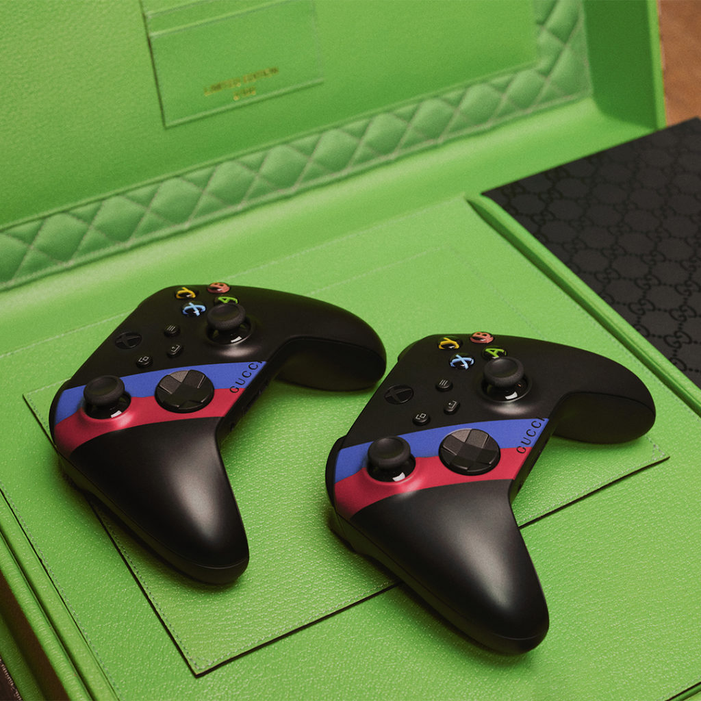 附有兩個 Xbox 遊戲控制器，控制器也印有紅綠 Web 條紋。